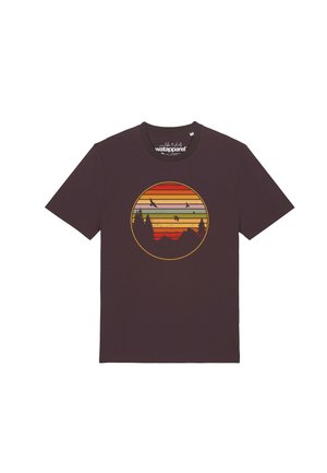 T-shirt marron foncé avec un graphisme rond d’un coucher de soleil rayé coloré, des oiseaux en vol, des silhouettes de montagnes et des pins.