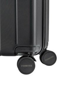 Schwarzer Hartschalenkoffer mit strukturierter Oberfläche, ausgestattet mit zwei robusten Rädern und einem sichtbaren Logo auf der Radoberfläche.