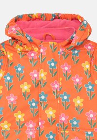 Orangenfarbene Jacke mit Blumenmuster, ausgestattet mit einem pinken Fleecefutter, Kapuze mit Gummi und lächelnden Blumenmotiven in Blau, Gelb und Pink.