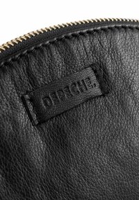 Bolsa de cuero negra con una superficie texturizada, cremallera dorada y una etiqueta de marca en relieve. Los acentos incluyen costuras a lo largo del borde.