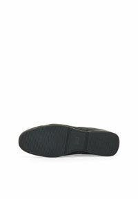 Svart gummisula med struktur för grepp, med horisontella och vertikala räfflor, samt en något upphöjd hälsektion.