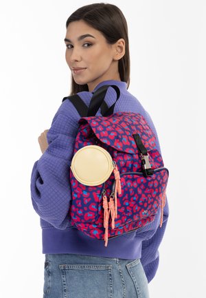 Rucksack mit einem Design in pink-lila Leopardenmuster, einer runden gelben Akzentuierung, Reißverschluss und strukturierten schwarzen Tragegurten.