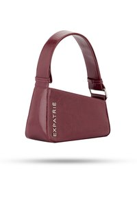Burgundi színű, vegán bőrből készült táska, háromszögletű forma, lapos fogantyú és ezüst "EXPATRIÉ" logó az oldalán. Simább textúra, minimalista design.