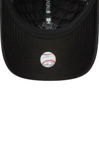 Cappellino da baseball nero con fodera imbottita e un adesivo circolare bianco con un design di baseball sulla visiera.