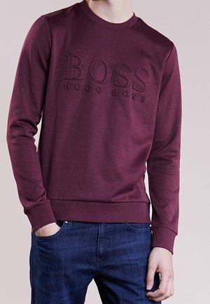 Felpa crewneck color bordeaux con logo in rilievo "BOSS HUGO BOSS" sul davanti. Presenta polsini e orlo a costine, realizzata in un tessuto morbido.