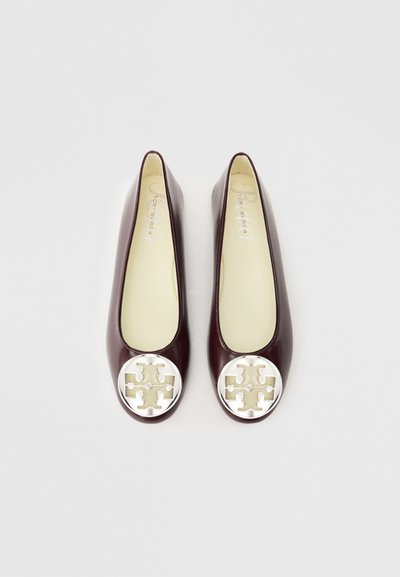 Burgundské lakované baleríny s okrúhlym strieborným logom na špičke, s hladkou textúrou a minimalistickým dizajnom.