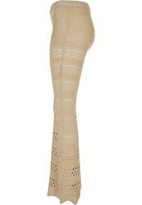 Pantalon en maille beige avec des rayures horizontales alternant entre unie et ajourée, cintré aux hanches et évasé en bas.