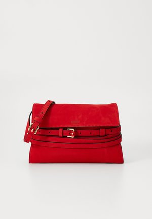 Red suede handbag with a flap closure, featuring a detachable strap, gold-tone hardware, and a decorative belt accent around the body.