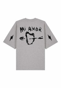T-shirt gris avec texte noir « Mi Amor », un cœur traversé par une flèche en illustration, et des éclairs noirs sur chaque manche.