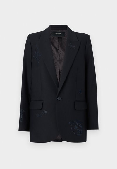 Μαύρο σακάκι με ένα κουμπί, με γιακά με σχισμή, τσέπες με καπάκι και διακριτικά σκοτεινά κεντημένα αστέρια και αφηρημένα σχέδια στο μπροστινό μέρος και στα μανίκια.