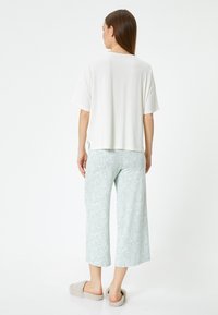 Haut blanc, ample et à manches courtes, associé à un pantalon court à motifs bleu clair. Tissu doux et coupe décontractée pour plus de confort.