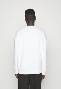 Witte crewneck sweatshirt met lange mouwen, met ribgebreide boorden en zoom. Glad van textuur met een ontspannen pasvorm. Effen achterkant, geen zichtbare graphics.