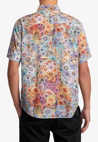 Košile s krátkým rukávem s živým květinovým vzorem obsahujícím mnohobarevné květiny a motýly na světlém pozadí. Lehká látka.