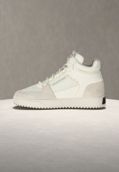 Λευκό ψηλό αθλητικό παπούτσι με πάνελ από σουέντ και δίχτυ, κλείσιμο με κορδόνια και λεπτομέρειες με αστέρι στη μία πλευρά, τοποθετημένο σε φωτεινή επιφάνεια με ουδέτερο φόντο.