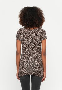 Majica kratkih rukava s uzorkom leopard, s okruglim izrezom i dužim stražnjim rubom. Mekani, lagani materijal s suptilnom teksturom.