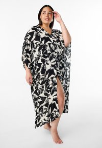 Svart och vitmönstrad kimono med V-ringning, lösa ärmar och en h�ögt skuren slits, tillverkad av lättviktig tyg.
