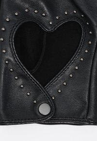 Guante de cuero negro sin dedos con un recorte en forma de corazón y tachuelas de metal plateado alrededor del recorte y en el cierre de broche de la muñeca.