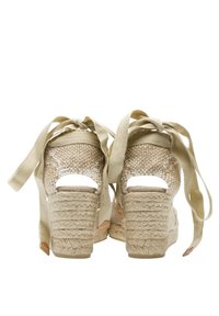 Sandali con zeppa in espadrilles beige, con tomaia in tessuto intrecciato, apertura sul retro e lacci in raso. Presentano un tacco in corda testurizzata con una base solida.