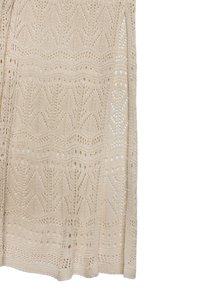 Beige gestrickter Pullover mit einer offenen Musterung, die Zickzack- und Blumenmotive zeigt. Weiche Textur, lockerer Schnitt und seitliche Schlitze am Saum.