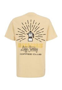 Camiseta de algodón amarilla claro con un gráfico negro de una cafetera y un diseño de ráfagas de sol, con el texto "Club del Café de Domingo Perezoso".