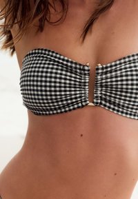Sort og hvid gingham bandeau bikini top med rynket stof og guldfarvet detalje i midten, glat tekstur og skulderfri design.