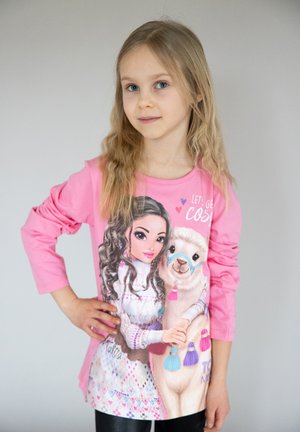 Rosa Langarm-T-Shirt mit einem grafischen Design eines Mädchens mit langem Haar und einem Lama, verziert mit bunten Quasten und Mustern.
