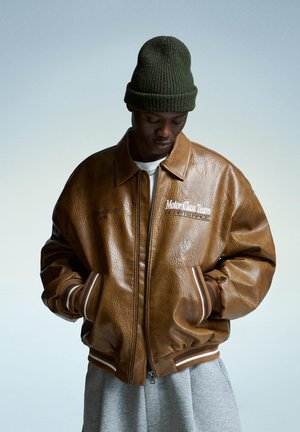Brown leather bomber jacket with a shiny texture, featuring a zip closure, ribbed cuffs, and embroidered "MotorClass Team" detail.
