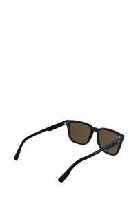 Occhiali da sole in plastica nera con montatura quadrata e lenti marroni. Presentano aste sottili con dettagli argentati per un aspetto elegante.