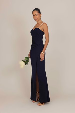 Navy evening gown with a fitted bodice, sweetheart neckline, and pearl-accented straps. Features a side slit and a smooth, textured fabric.