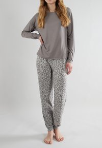 Grå långärmad topp kombinerad med grå mönstrade pyjamasbyxor med en subtil leopardprint och smala muddar; mjuk tygtextur.