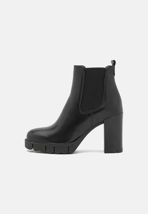 Bottines en cuir noir avec un talon carré chunky, des panneaux latéraux élastiques et une semelle texturée. Équipées d'une languette à l'arrière pour un enfilage facile.