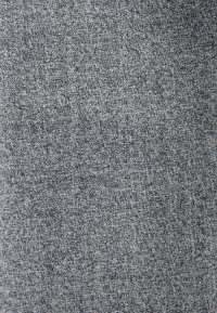 Gros plan sur une texture de tissu gris grossier avec un motif dense et irrégulier de petites boucles et fibres.