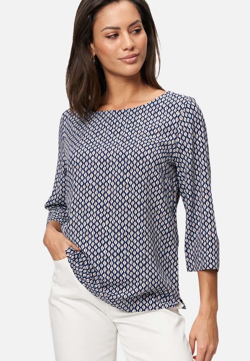 Navyblauwe blouse met een geometrisch patroon in crème, met driekwartmouwen en een losse pasvorm. Soepele textuur en ronde halslijn.