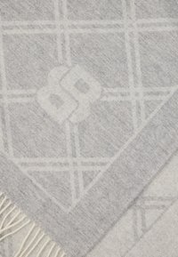 Γκρι υφαντή κουβέρτα ριχτάρι με γεωμετρικό μοτίβο και κρόσσια στις άκρες, κατασκευασμένη από μαλακό υλικό, με διακριτική υφή και γυαλάδα.