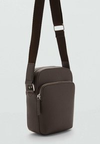Borsa a tracolla sintetica marrone con finitura testurizzata, tracolla regolabile e due scomparti con zip. Forma rettangolare compatta.