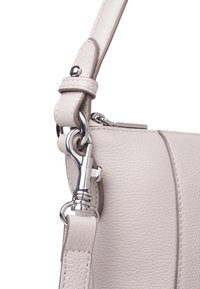 Helle beige Lederhandtaschen-Tragegurt mit strukturierter Oberfläche, ausgestattet mit silbernem Metallzubehör und einem auffälligen Clip zur Befestigung.