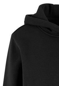 Hanorac negru cu glugă pliată și textură simplă, netedă a țesăturii vizibilă pe umăr și partea superioară a pieptului.