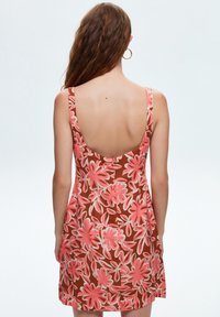 Brown floral dress with pink flower patterns, spaghetti straps, and a low-cut back. Lightweight fabric, knee-length, casual design.