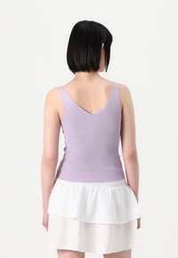 Lilla ribbet tanktop med V-formet rygg, kombinert med en hvit todelt skjørt. Toppen har tynne stropper og en tettsittende design.