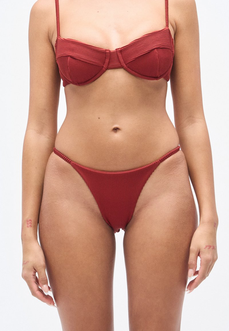 Κόκκινο σετ μπικίνι με ριμπ ύφασμα που περιλαμβά νει μια δομημένη τοπ μπουστάκι με λεπτές τιράντες και σλιπ με ψηλή κοπή και ελάχιστη κάλυψη, με υφή στο ύφασμα.