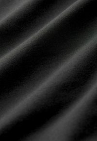 Černá tkanina s hladkou texturou, která se vyznačuje jemným leskem a měkkými sklady, ukazujícími její lehkost a flexibilitu.