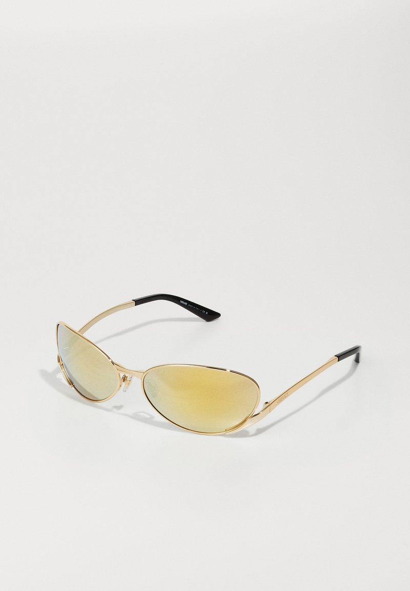 Ochelari de soare cu ramă aurie și lentile cu gradient de chihlimbar. Formă subțire de tip cat-eye, design ușor din metal și vârfuri ale templelor cu textură neagră.