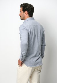 Grijze langemouwen shirt met een button-down kraag, op maat gemaakt pasvorm en een ronde zoom. Gemaakt van zachte stof met een subtiele textuur.