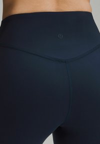 Hochtaillierte navy Leggings aus elastischem Material, mit flachen Nähten und einem kleinen Logo über dem Bund für minimale Markenpräsenz.