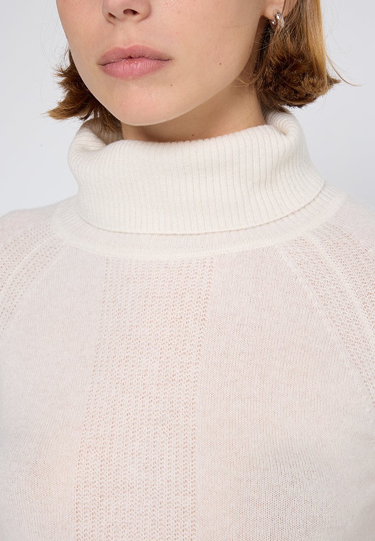 Cremfarbener Rollkragenpullover mit geripptem Kragen und strukturiertem Strickmuster, aus leichtem, semi-transparentem Stoff gefertigt und in taillierter Form.