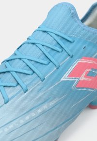 Svijetloplave nogometne kopačke s teksturiranim materijalom, usklađenim vezicama i ružičastim geometrijskim logotipom sa strane.