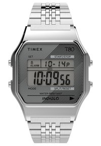 Montre numérique avec bracelet en acier inoxydable, boîtier octogonal en argent, cadran gris à motifs et écran lumineux. Équipée de boutons pour les réglages.