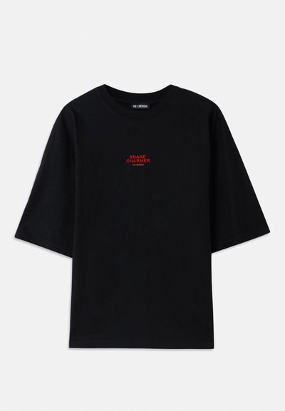 T-shirt en coton noir avec des manches courtes et un col rond. Présente un graphique rouge "SNAKE CHARMER" sur la poitrine.