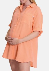 Kurzarmhemd aus leichtem orangefarbenem Stoff, mit Knopfleiste, Brusttasche und einem lockeren, oversize Schnitt mit abgerundetem Saum.