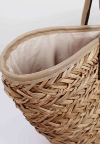 Kudottu olkakoriminen laukku, jossa on beige nahkareunus ja vuori. Sisus on muotoilematon, kevyttä kangasta.